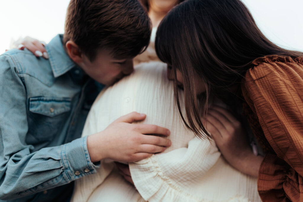 kids kissing mother's baby bump