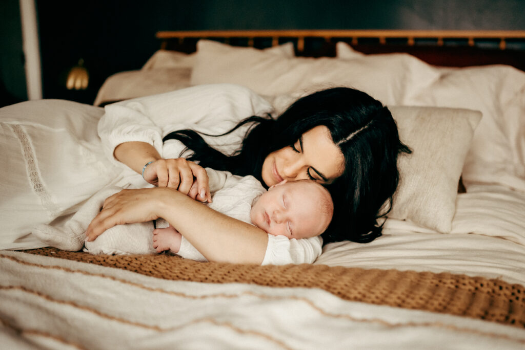 mother hugging newborn in bed during newborn session
