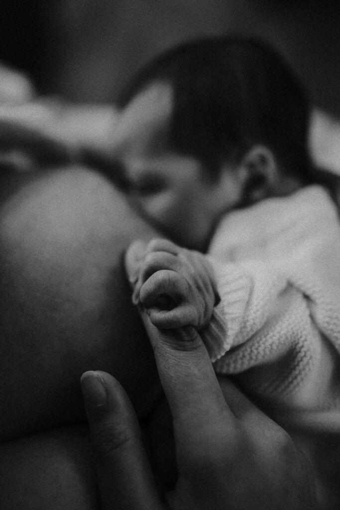 newborn nursing from mom holding hand 