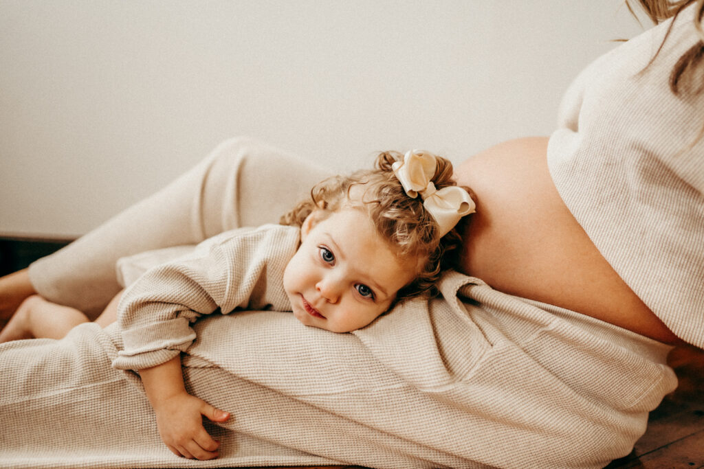 daughter laying on mom lap. baby bump showing