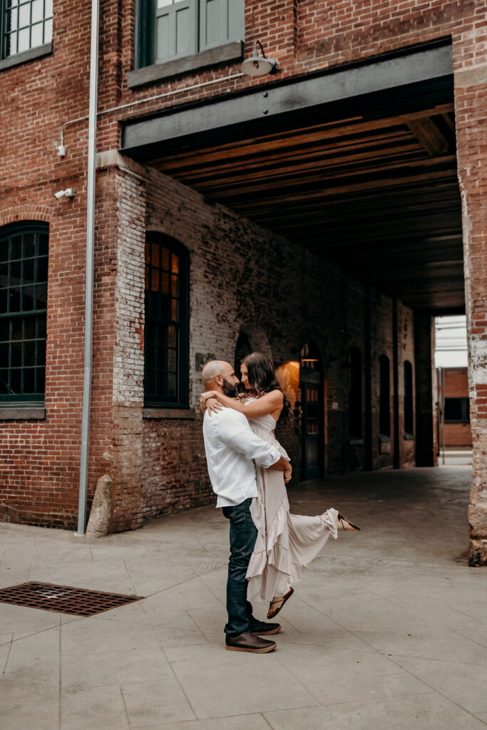 engagement photography in pennsylvania holding each other in front of building
