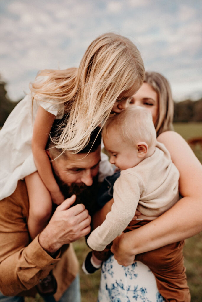 family photos in Pennsylvania at farm. daughter kissing brother on dads shoulder.