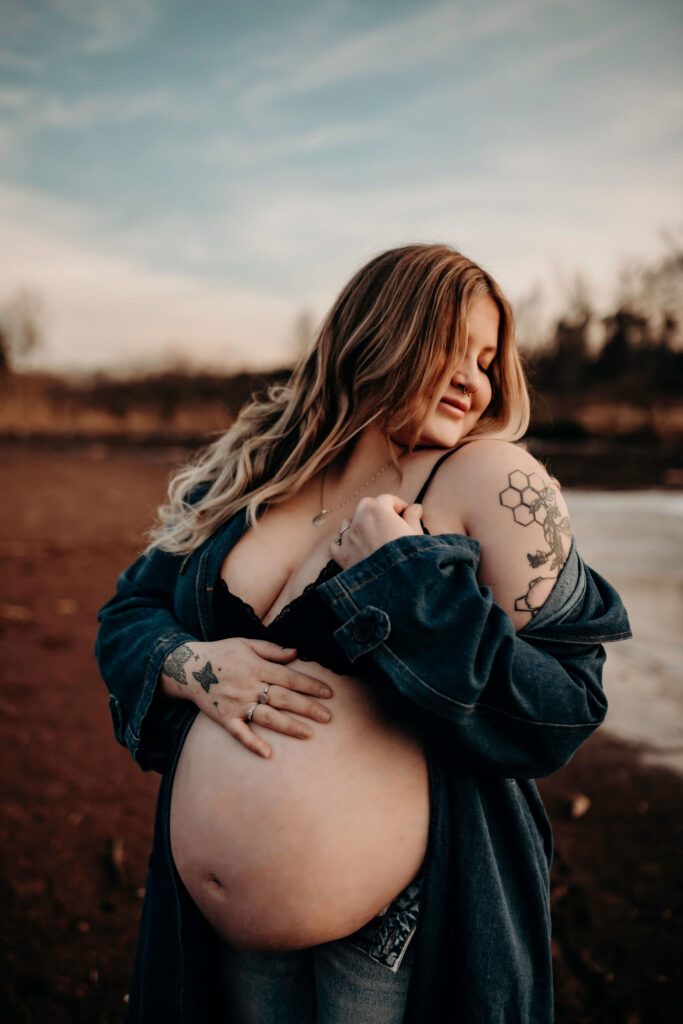 pregnancy photographer of mom to be showing off belly outside in winter