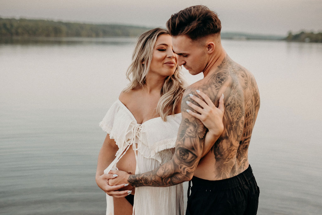 couple embracing each other standing in lake during maternity photos