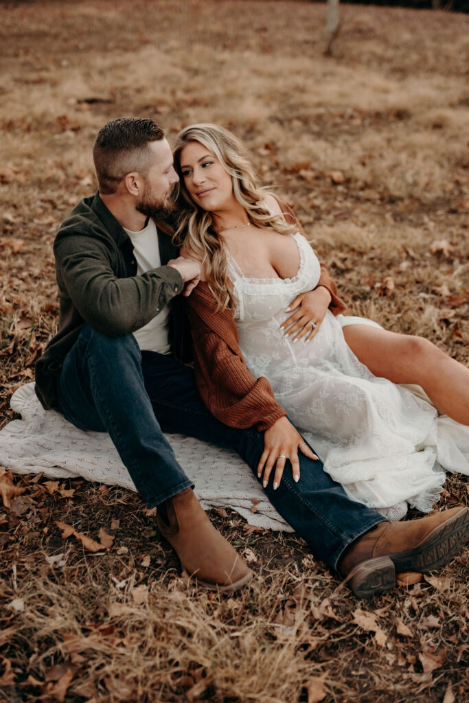 mom and dad to be sitting on ground during fall maternity photos
