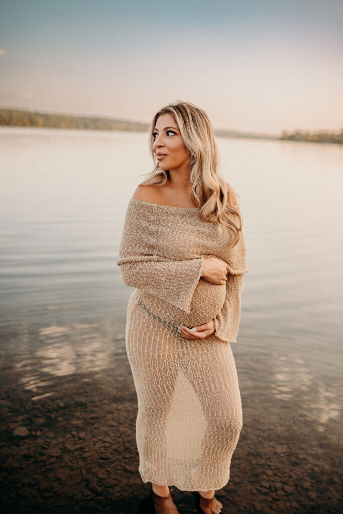 mom holding bump during maternity photos in summer
