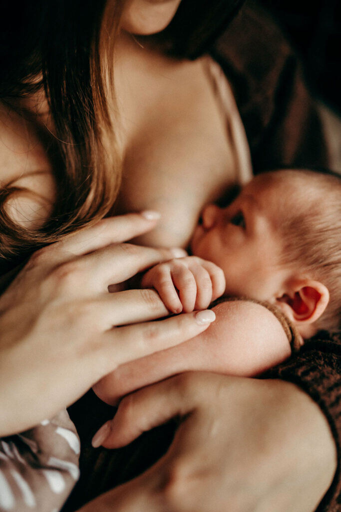 mom holding hand of newborn during photoshoot