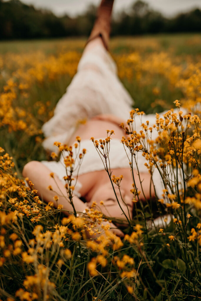 Spring maternity client laying in ground with flowers.