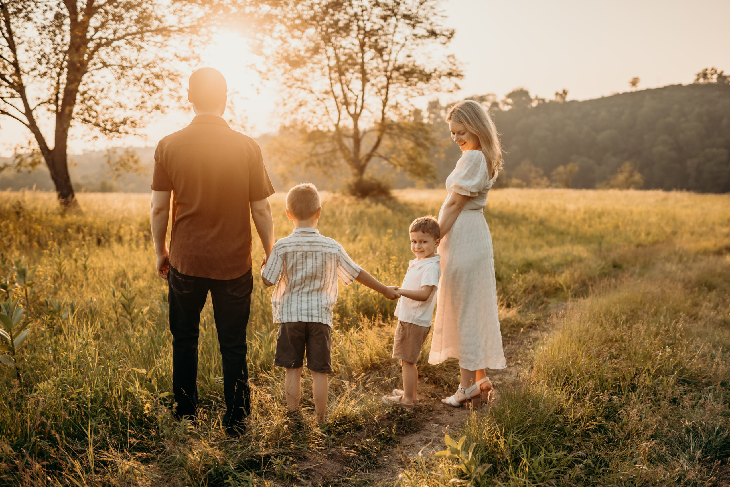 family standing in field at sunset photoshoot