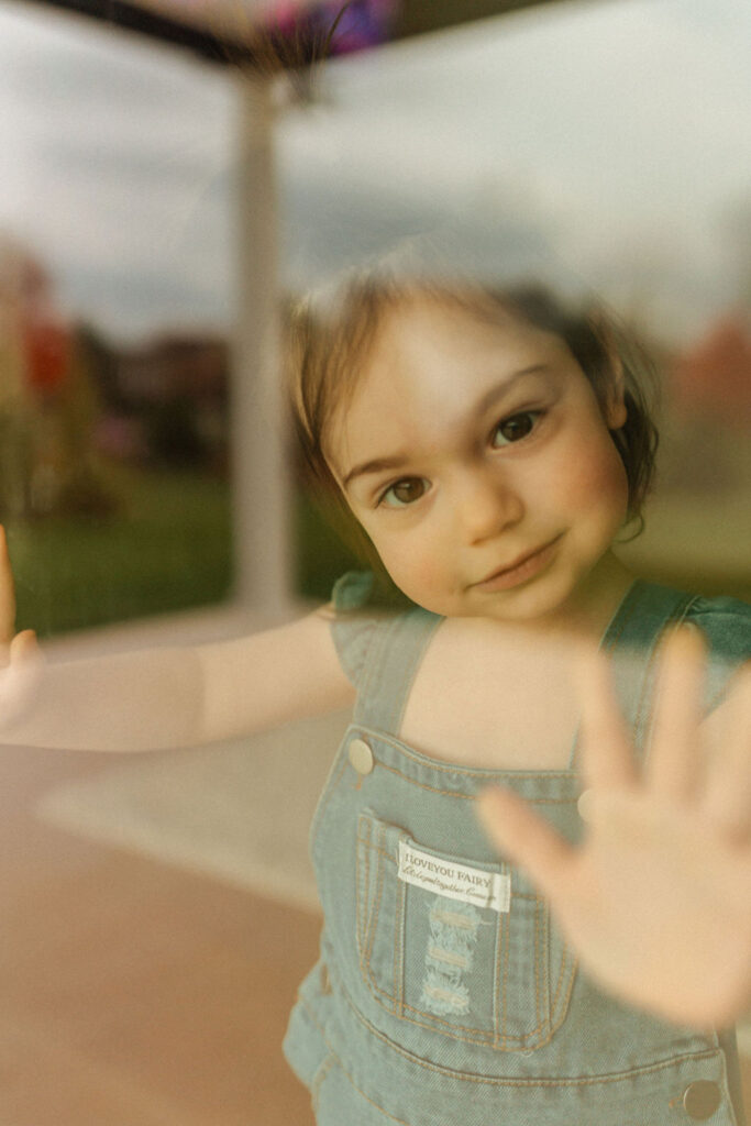 daughter looking out window in home photo session