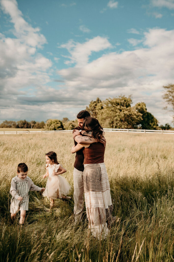 mom and dad hugging while children running in authentic family photos in march