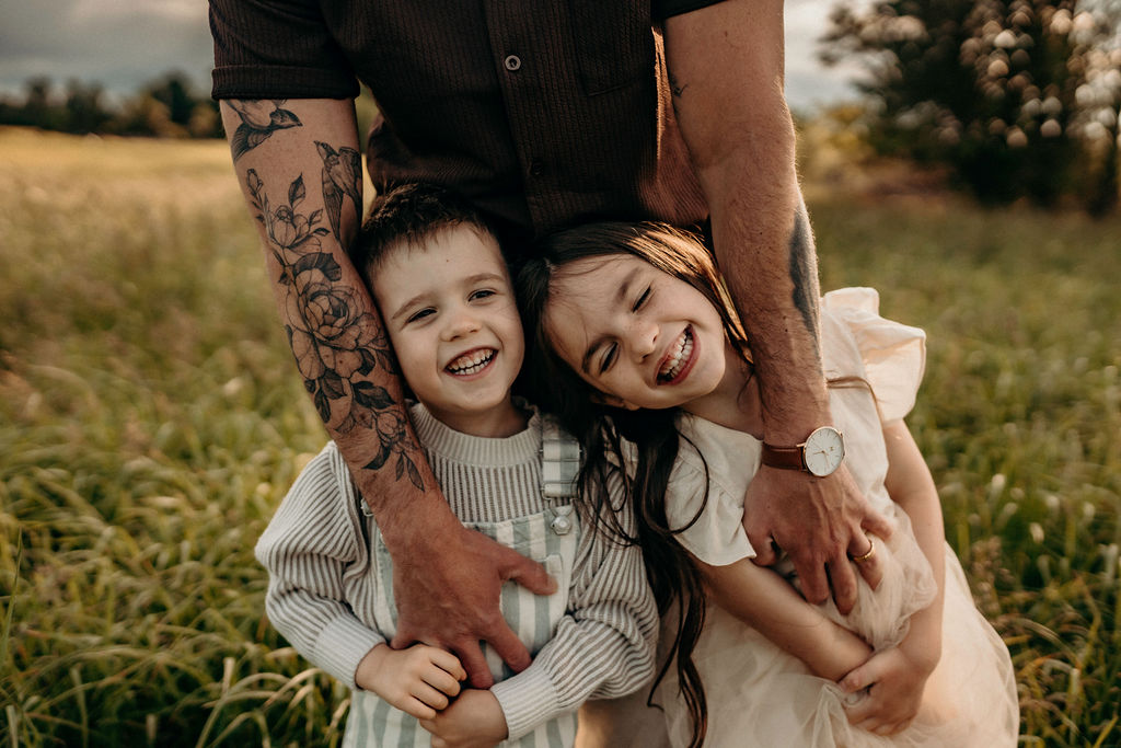 children laughing in dads arms 
