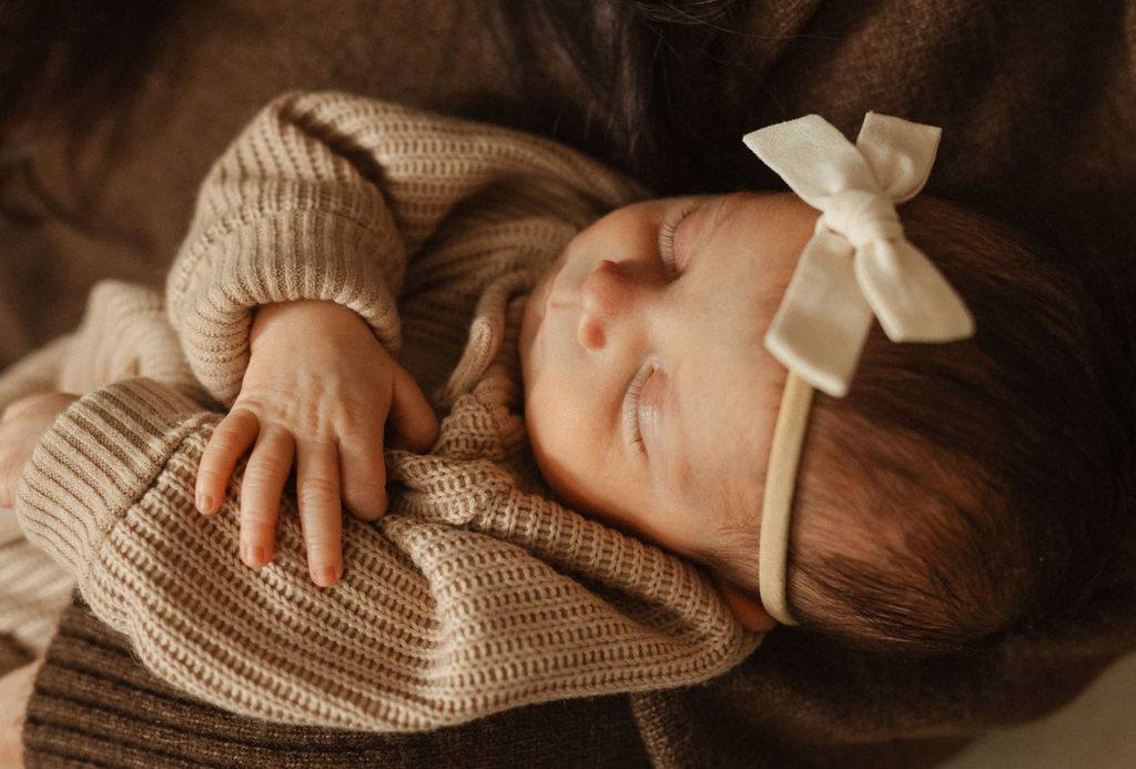 sleeping newborn baby , neutral sweater with bow vibe