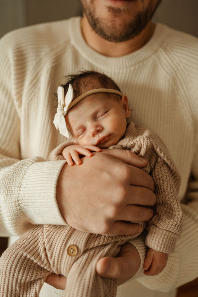 dad holding sleepy baby post in home