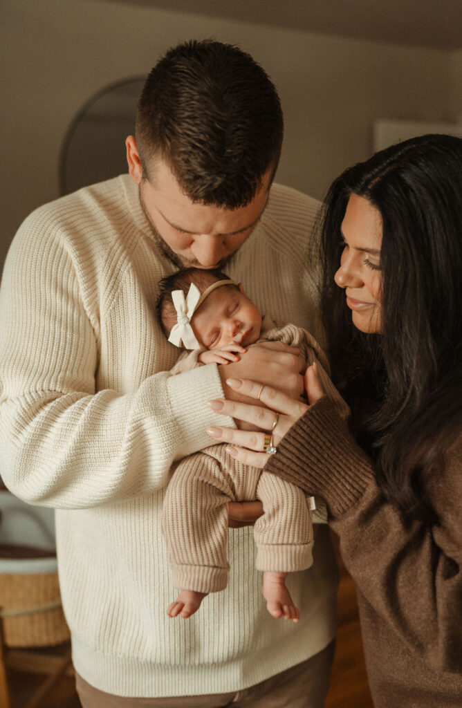 dad kissing baby daughter and mom hugging embraced during newborn lifestyle photos in bethlehem PA