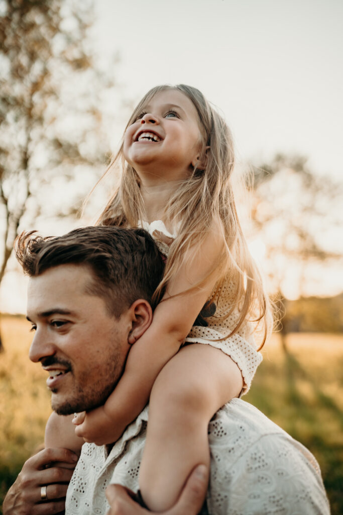 dad holding daughter on shoulder having a good time at family photos